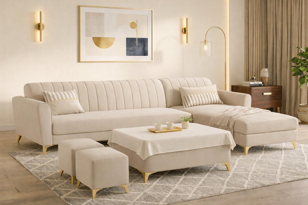 A modern beige sectional sofa with a chaise lounge and matching ottomans in a bright, contemporary living room. The sofa features vertical channel tufting on the backrest and is supported by slim gold-toned legs, set on a patterned rug with a matching coffee table and throw blanket.
